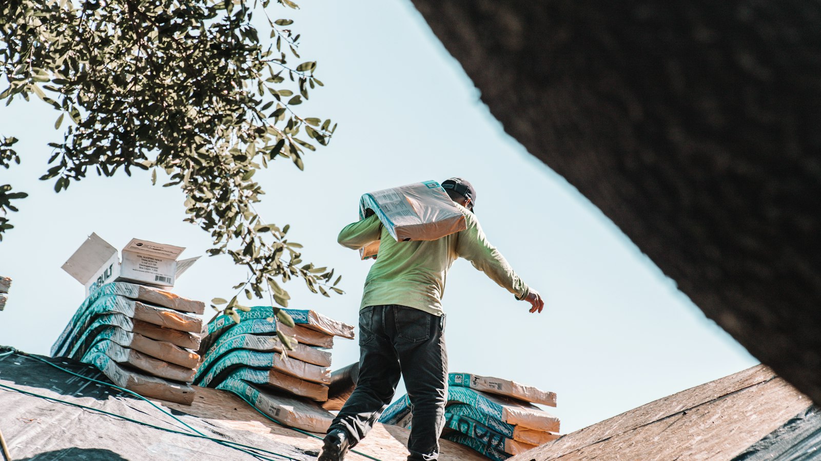 Roofing contractor carrying shingles across a residential roof